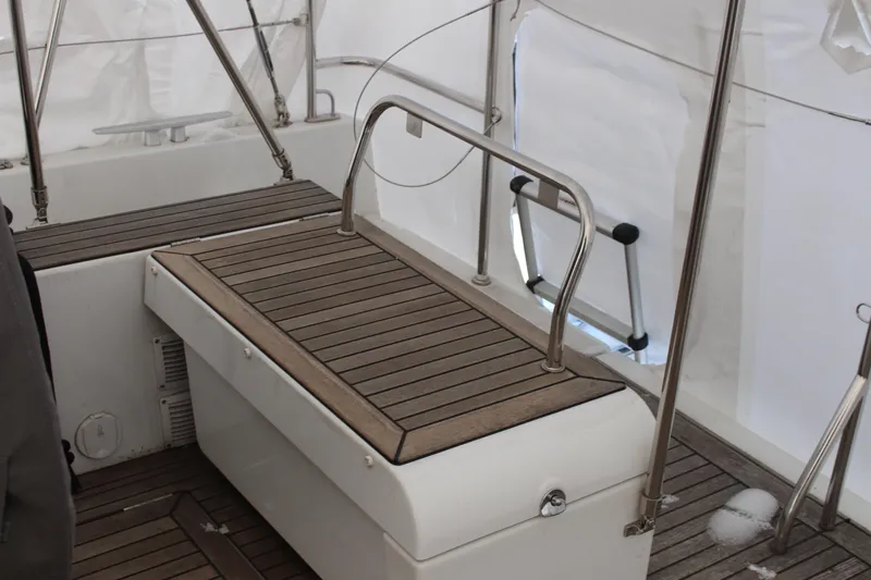 Spellbound Yacht Photos Pics Port Aft helm seat w storage. Back cushion stored for winter. Beneteau Oceanis Yacht 54, 2022 model, featuring a sleek wooden deck design.