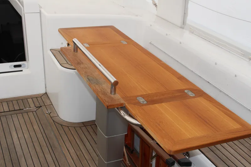 Spellbound Yacht Photos Pics Wooden table on Beneteau Oceanis Yacht 54, 2022 model, with sleek design and metal accents.