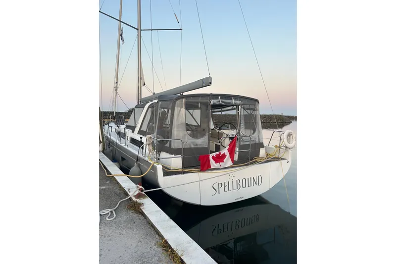 Spellbound Yacht Photos Pics 2022 Beneteau Oceanis Yacht 54 docked, displaying a Canadian flag at sunset.