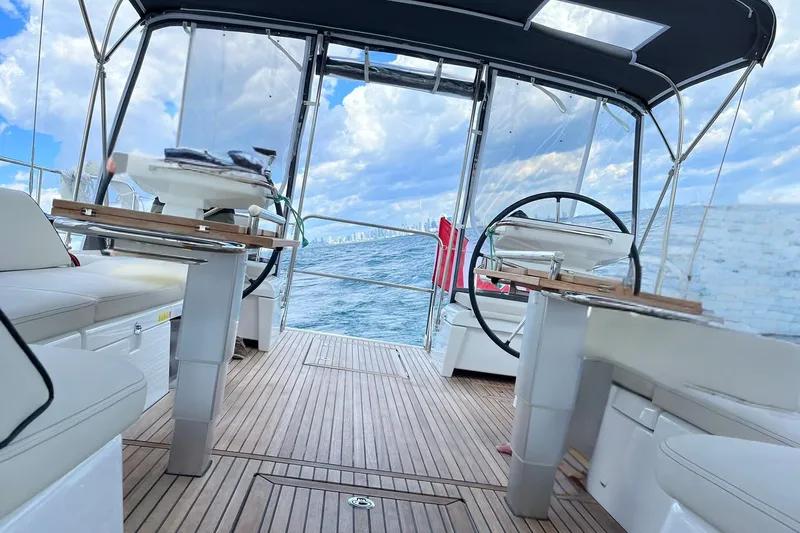 Spellbound Yacht Photos Pics Looking aft, under sail. Photoshop to remove the owners face. Luxurious 2022 Beneteau Oceanis Yacht 54 interior with wooden deck and dual steering wheels.