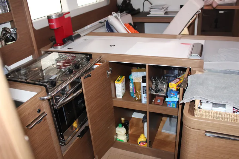 Spellbound Yacht Photos Pics Modern kitchen interior of 2022 Beneteau Oceanis Yacht 54 with open cabinets and appliances.