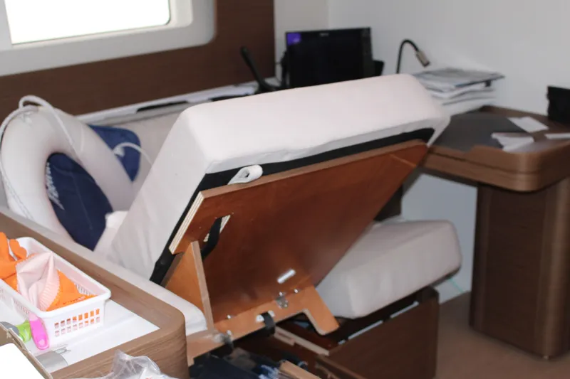 Spellbound Yacht Photos Pics Witerization clutter. Nav desk & settee, port side and forward in the saloon. Interior of 2022 Beneteau Oceanis Yacht 54 with adjustable seating and desk area.