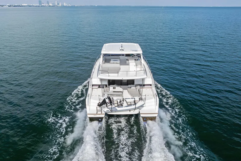 Closer To The Sun Yacht Photos Pics 2025 Leopard 53 Powercat cruising on open water, city skyline in background.