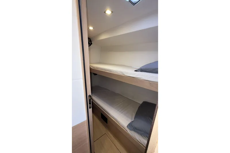  Yacht Photos Pics Bunk beds in 2019 Amel 50 yacht cabin, featuring modern lighting and cozy bedding.