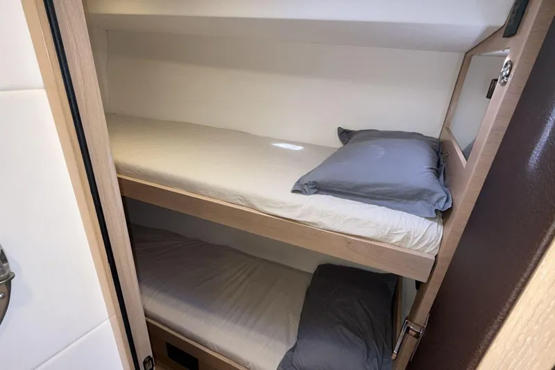  Yacht Photos Pics Bunk beds in 2019 Amel 50 yacht cabin, featuring wooden frames and gray pillows.