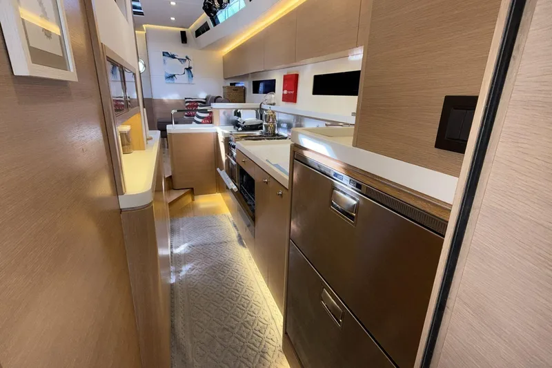  Yacht Photos Pics Modern kitchen interior of 2019 Amel 50 yacht, featuring sleek wood cabinetry and stainless steel appliances.