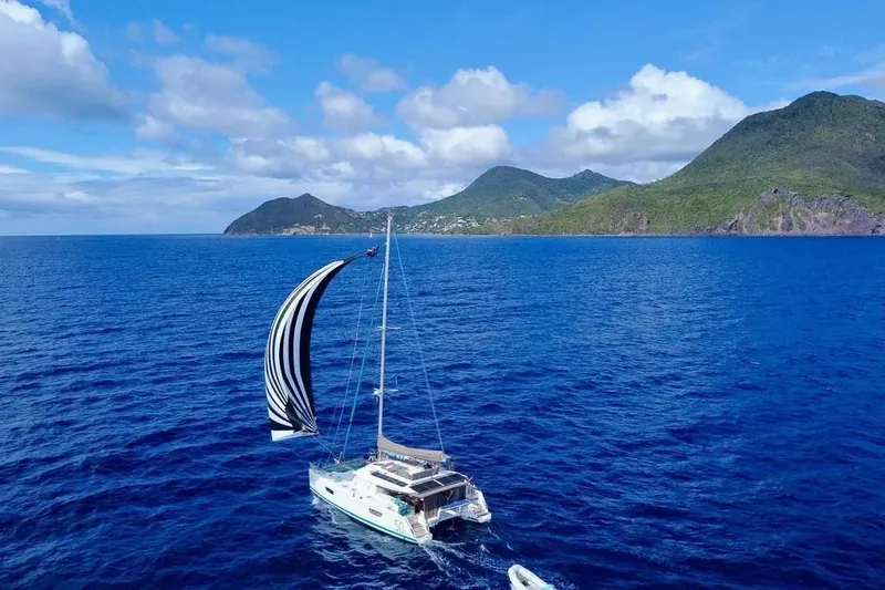 Xclip Yacht Photos Pics 2015 Fountaine Pajot SABA 50 sailing in blue ocean near lush green mountains.