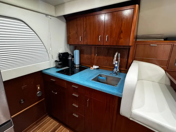 Sweet Melissa Yacht Photos Pics Luxurious kitchen interior of 1992 Ocean Yachts 48 Convertible with wooden cabinets and blue countertop.