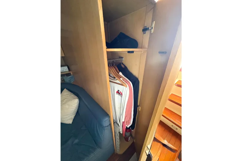  Yacht Photos Pics Cozy cabin closet in 1993 Tiara Yachts 43 Open, featuring hanging clothes and a sofa.