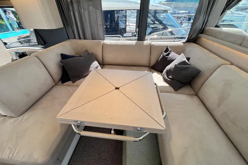  Yacht Photos Pics Luxurious interior of 2025 Nimbus 495 Flybridge yacht with beige seating and modern table.