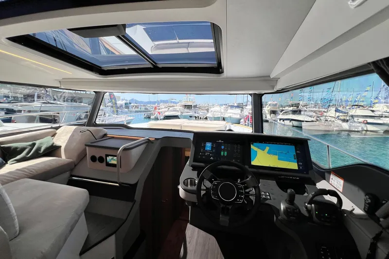  Yacht Photos Pics Interior view of 2025 Nimbus 495 Flybridge yacht cockpit with navigation screens and marina backdrop.