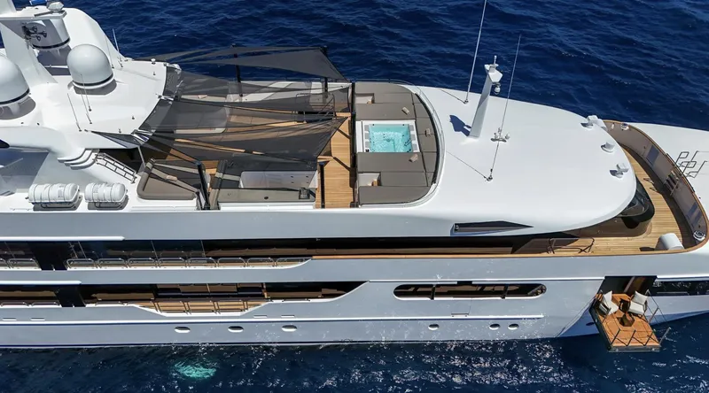 Magna Grecia Yacht Photos Pics Luxurious 1986 Custom Elsflether Werft yacht with sun deck and jacuzzi, cruising on blue ocean waters.