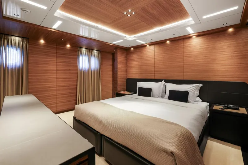 Magna Grecia Yacht Photos Pics Luxurious yacht bedroom with wood paneling, modern lighting, and a comfortable bed.