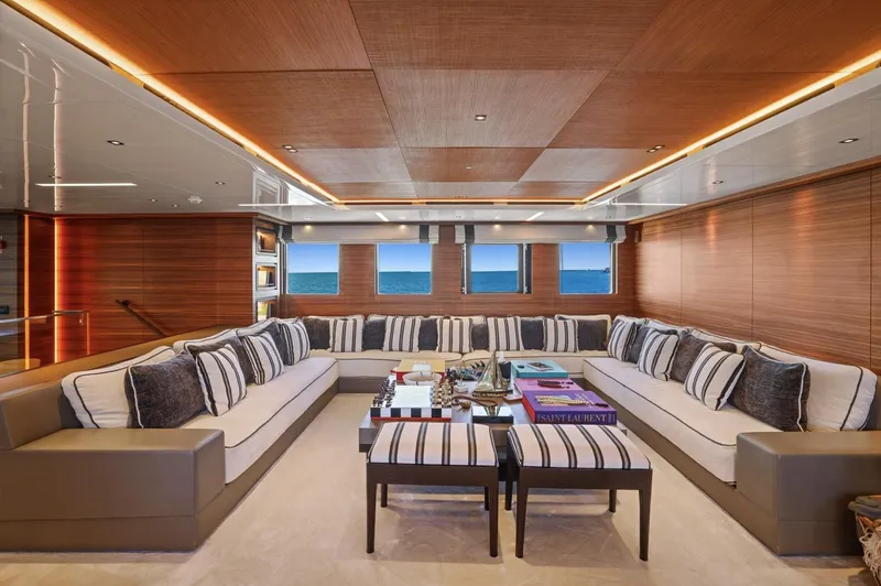 Magna Grecia Yacht Photos Pics Luxurious yacht interior with striped cushions, wooden paneling, and ocean view through windows.