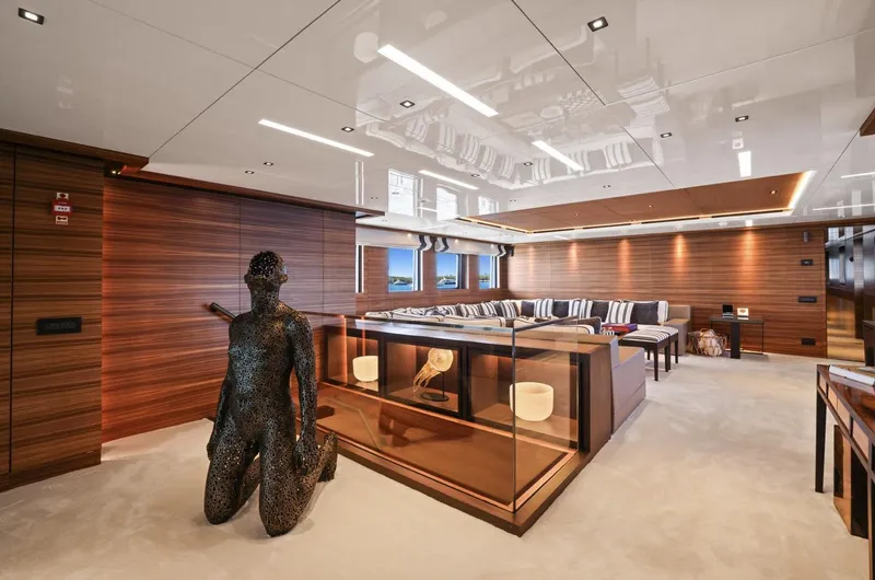 Magna Grecia Yacht Photos Pics Luxurious yacht interior with modern decor, featuring a unique sculpture and elegant wood paneling.