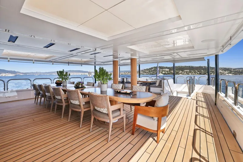 Magna Grecia Yacht Photos Pics Luxurious yacht deck with dining area, wooden flooring, and ocean view, Custom Elsflether Werft 1986.