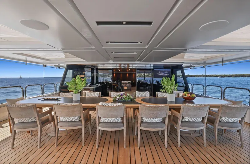 Magna Grecia Yacht Photos Pics Luxurious yacht deck with dining area, wooden furniture, and ocean view, Custom Elsflether Werft 1986.