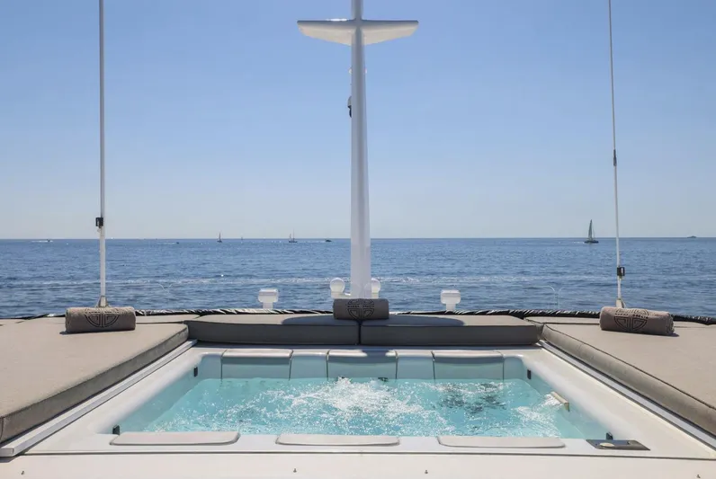 Magna Grecia Yacht Photos Pics Luxurious yacht deck with jacuzzi, ocean view, and clear blue sky.