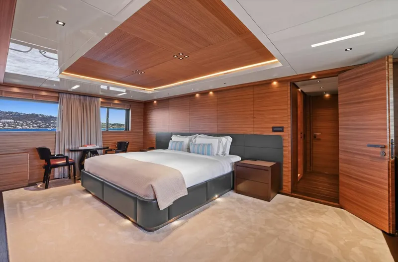 Magna Grecia Yacht Photos Pics Luxurious yacht bedroom with wood paneling, large bed, and scenic window view.