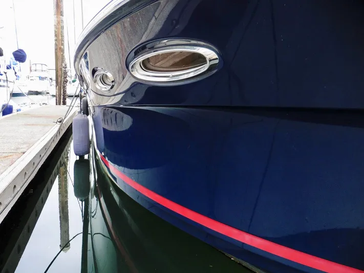  Yacht Photos Pics Close-up of 2015 Cutwater 30CB boat docked, featuring sleek blue hull and red stripe.