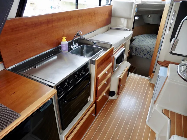  Yacht Photos Pics 2015 Cutwater 30CB boat interior with kitchen, sink, stove, and wood flooring.
