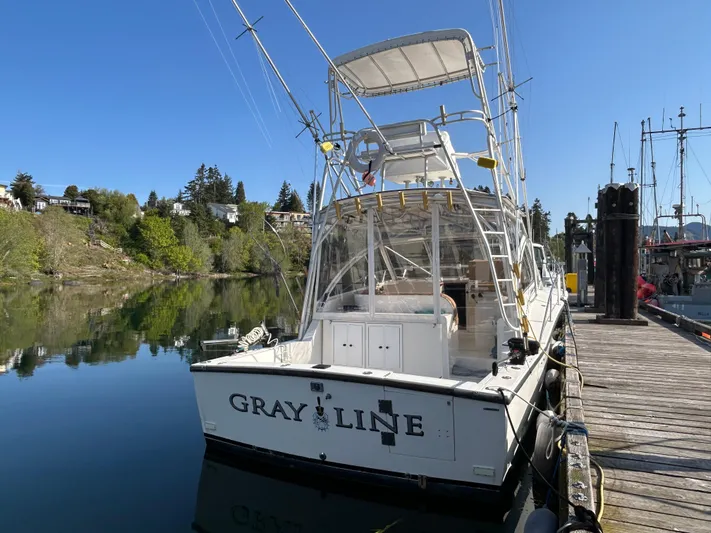  Yacht Photos Pics 1999 Carolina Classic 35 boat docked, clear sky, calm water, lush greenery in the background.