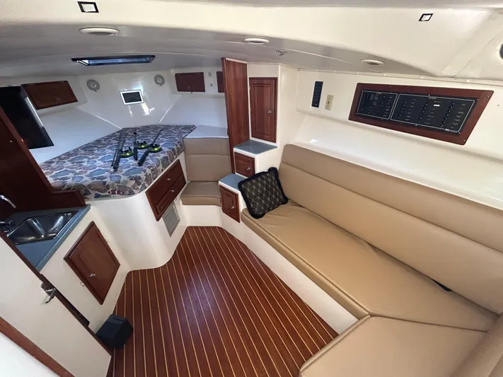  Yacht Photos Pics 1999 Carolina Classic 35 interior with beige seating, wood accents, and a compact kitchenette.