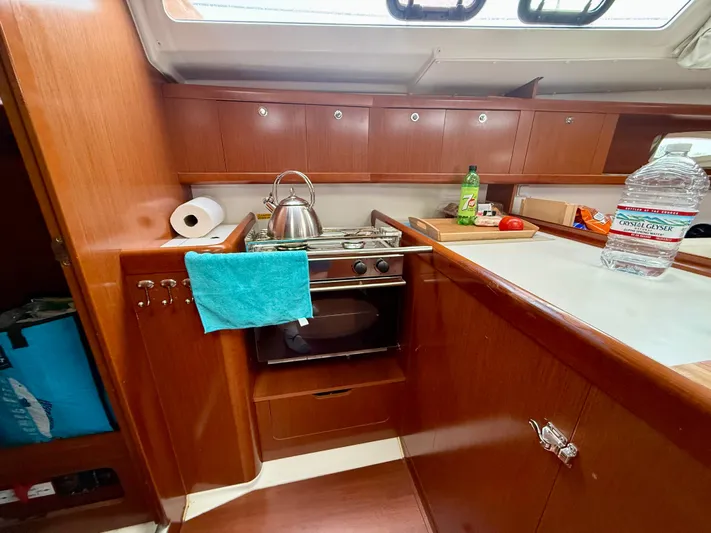  Yacht Photos Pics 2012 Beneteau Oceanis 37 yacht kitchen with stove, kettle, and wooden cabinetry.