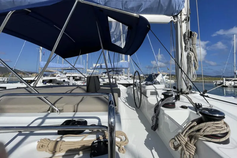 Skye Yacht Photos Pics 2023 Lagoon 50 yacht deck with ropes and steering wheel in a marina.