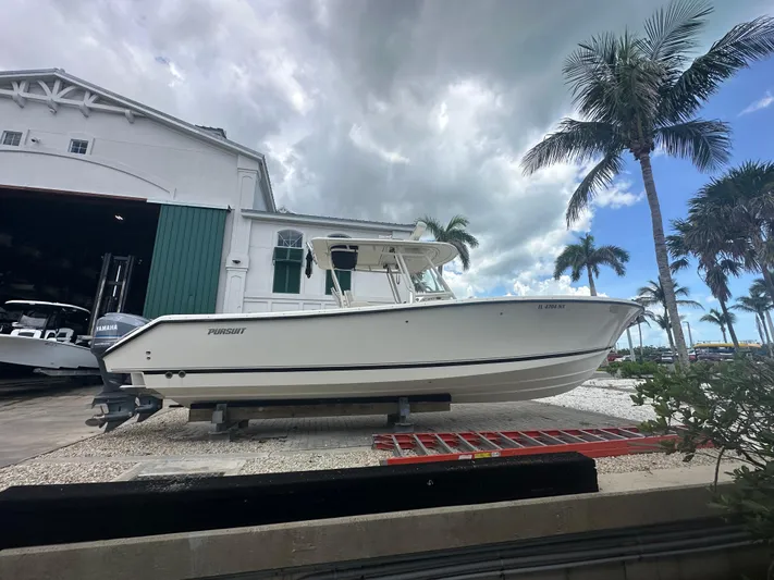  Yacht Photos Pics 2009 Pursuit C 310 Center Console boat on display near palm trees and a building.