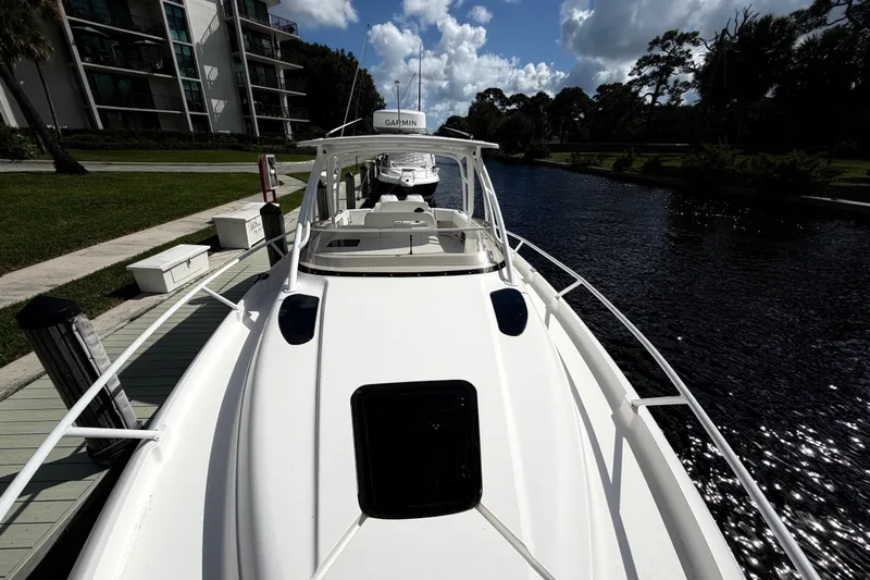 Watch Me Yacht Photos Pics 2008 Intrepid 350 Center Console boat docked by a canal under a partly cloudy sky.