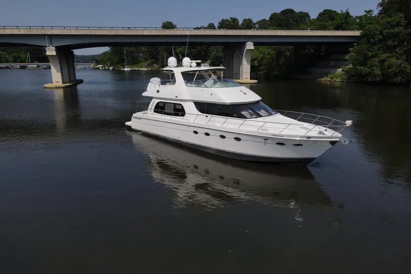 Mardi Gras Yacht Photos Pics 2006 Carver 56 Voyager yacht cruising under a bridge on a calm river.