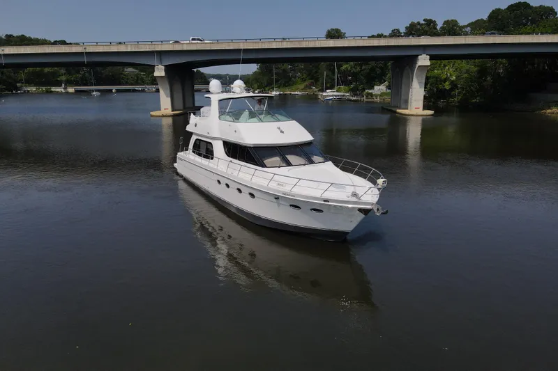 Mardi Gras Yacht Photos Pics 2006 Carver 56 Voyager yacht cruising under a bridge on a calm river.