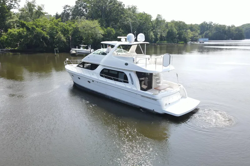 Mardi Gras Yacht Photos Pics 2006 Carver 56 Voyager yacht cruising on a serene river with lush greenery.