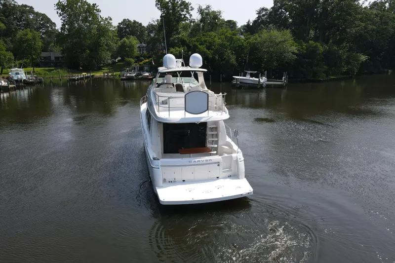 Mardi Gras Yacht Photos Pics 2006 Carver 56 Voyager yacht cruising on a serene river surrounded by lush greenery.