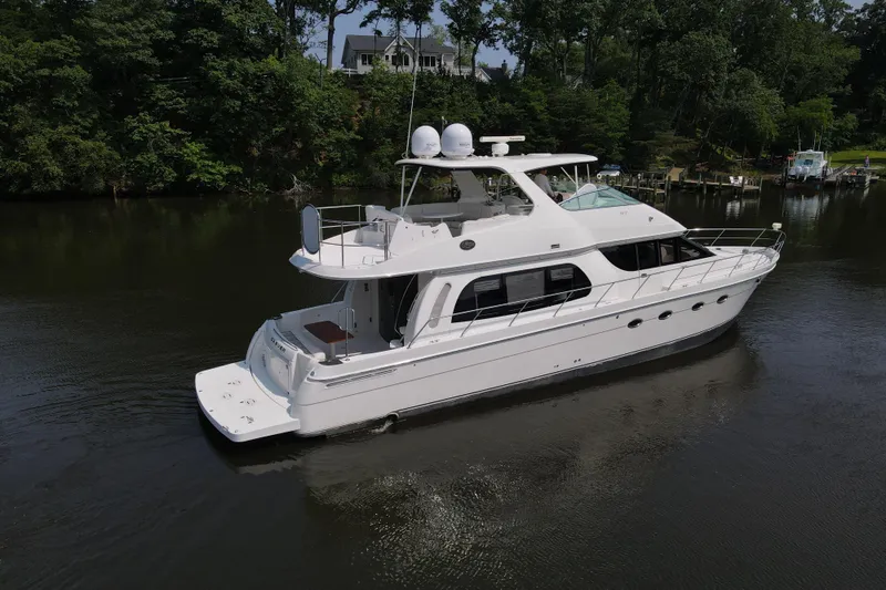 Mardi Gras Yacht Photos Pics 2006 Carver 56 Voyager yacht on a serene river, surrounded by lush greenery.