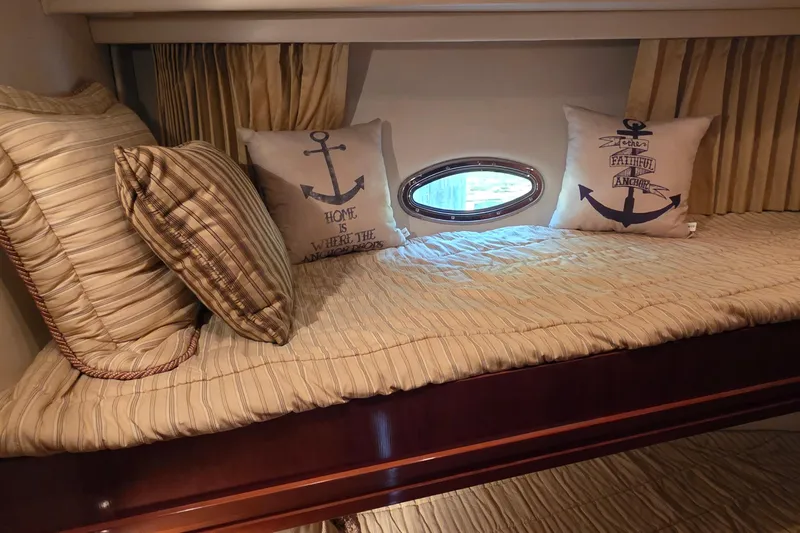 Mardi Gras Yacht Photos Pics Cozy cabin interior of 2006 Carver 56 Voyager with nautical-themed pillows and porthole window.