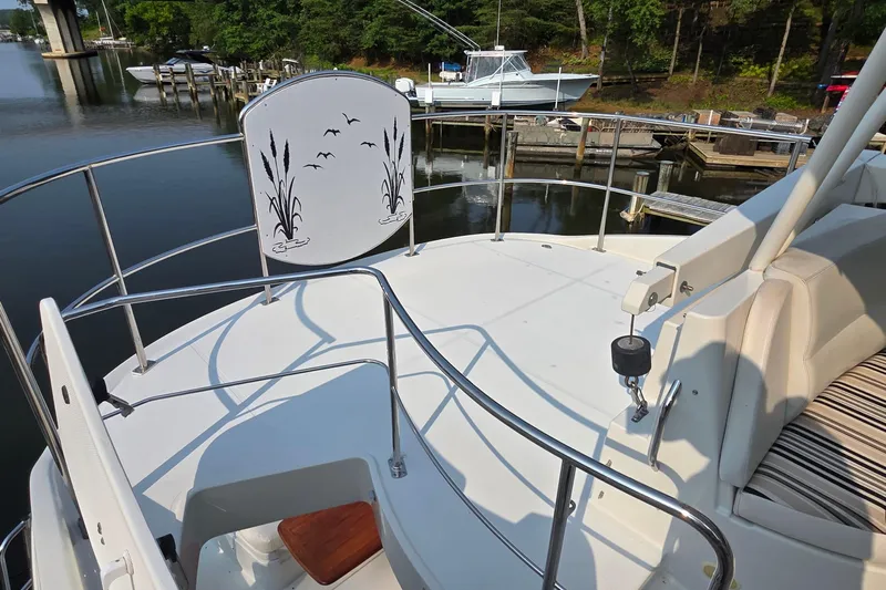 Mardi Gras Yacht Photos Pics 2006 Carver 56 Voyager yacht deck with railing, docked near serene waters and lush greenery.