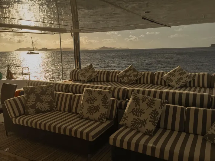 Ipharra Yacht Photos Pics Luxurious Sunreef 31m yacht deck with striped seating, ocean view, and sunset ambiance, 2009 model.