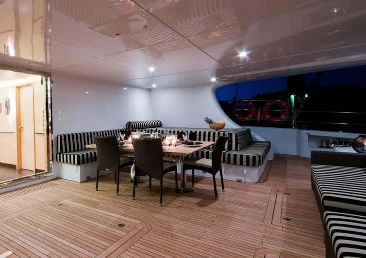 Ipharra Yacht Photos Pics Luxurious Sunreef 31m yacht deck with elegant dining area, striped seating, and ambient lighting, 2009 model.