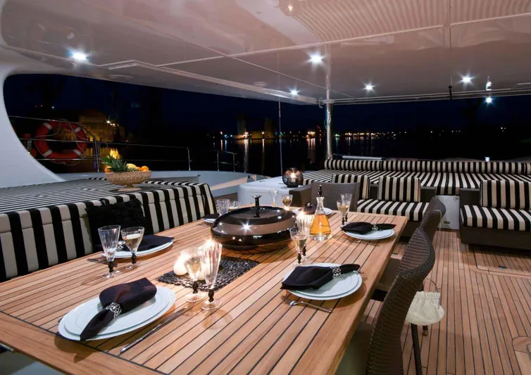 Ipharra Yacht Photos Pics Luxurious Sunreef 31m yacht deck with elegant dining setup, striped seating, and ambient lighting, 2009 model.