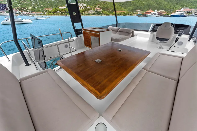 Mona Lisa Yacht Photos Pics 2024 Fountaine Pajot MY.6 yacht interior with seating, table, and helm, overlooking serene waters.