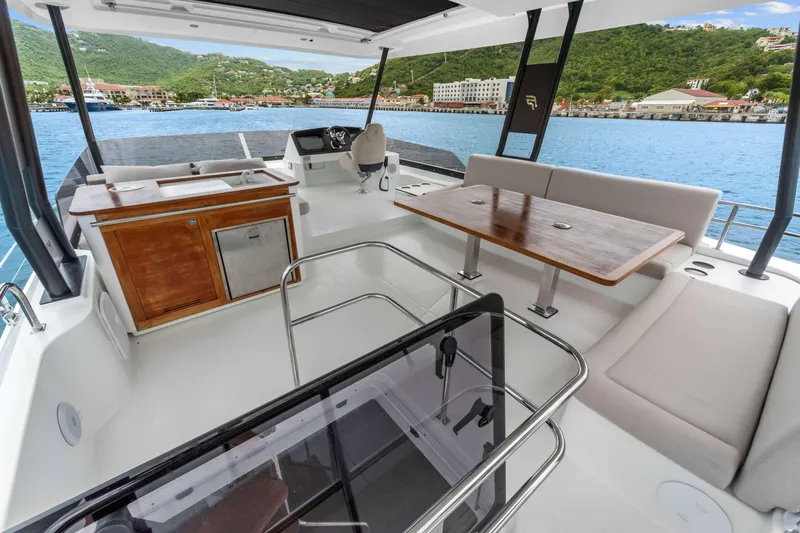 Mona Lisa Yacht Photos Pics 2024 Fountaine Pajot MY.6 yacht interior with seating, table, and helm, overlooking scenic harbor.