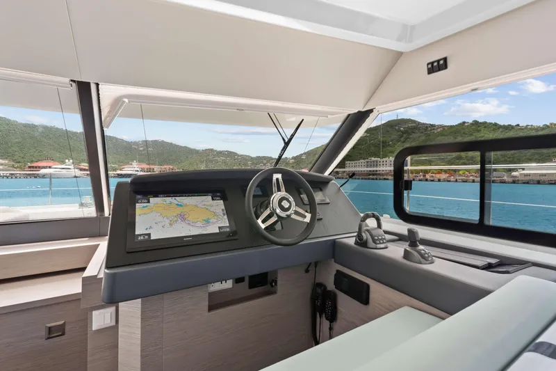 Mona Lisa Yacht Photos Pics 2024 Fountaine Pajot MY.6 yacht helm with navigation display, overlooking scenic marina.