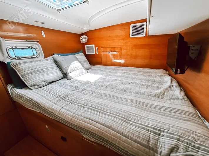 Kansakota Winds Yacht Photos Pics Cozy cabin interior of 2003 Lagoon 410-S2 catamaran with bed and porthole.
