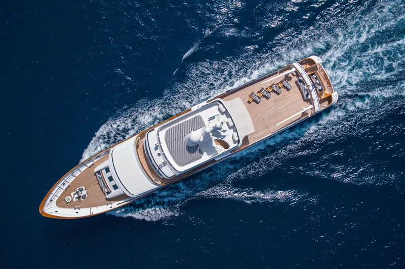 Monaco Yacht Photos Pics Aerial view of 1982 Feadship Classic yacht cruising on blue ocean waters.