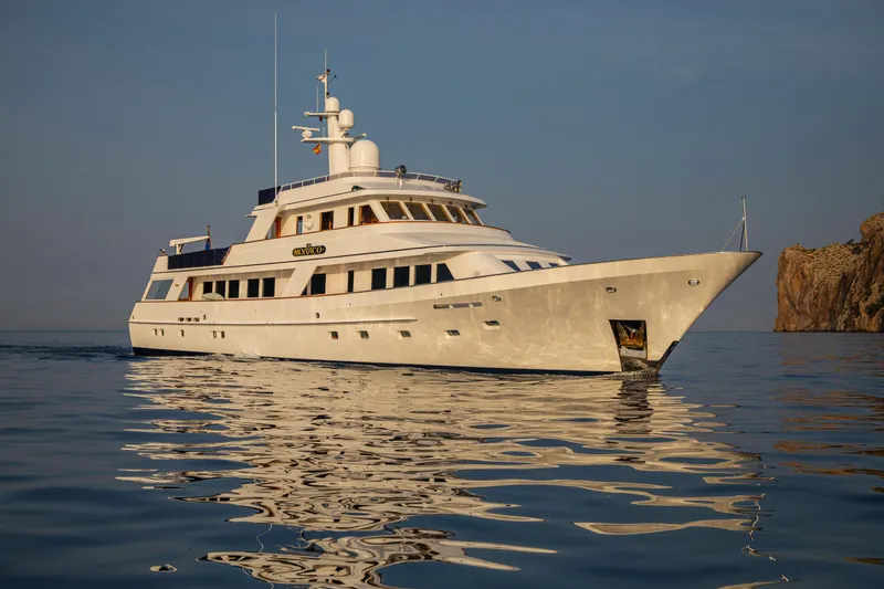 Monaco Yacht Photos Pics Luxury 1982 Feadship Classic yacht on calm sea near rocky coastline.