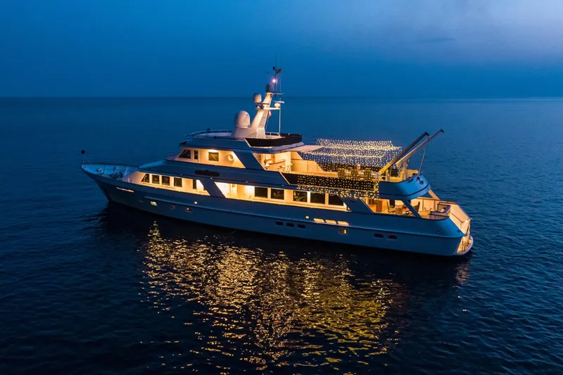 Monaco Yacht Photos Pics Luxurious 1982 Feadship Classic yacht illuminated at night on calm sea.