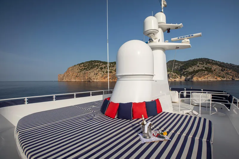 Monaco Yacht Photos Pics Luxurious 1982 Feadship Classic yacht deck with striped lounge, cushions, and scenic ocean view.