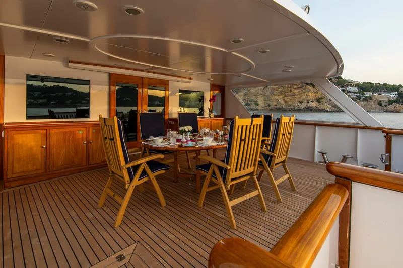 Monaco Yacht Photos Pics Luxurious 1982 Feadship Classic yacht deck with elegant dining setup and scenic ocean view.